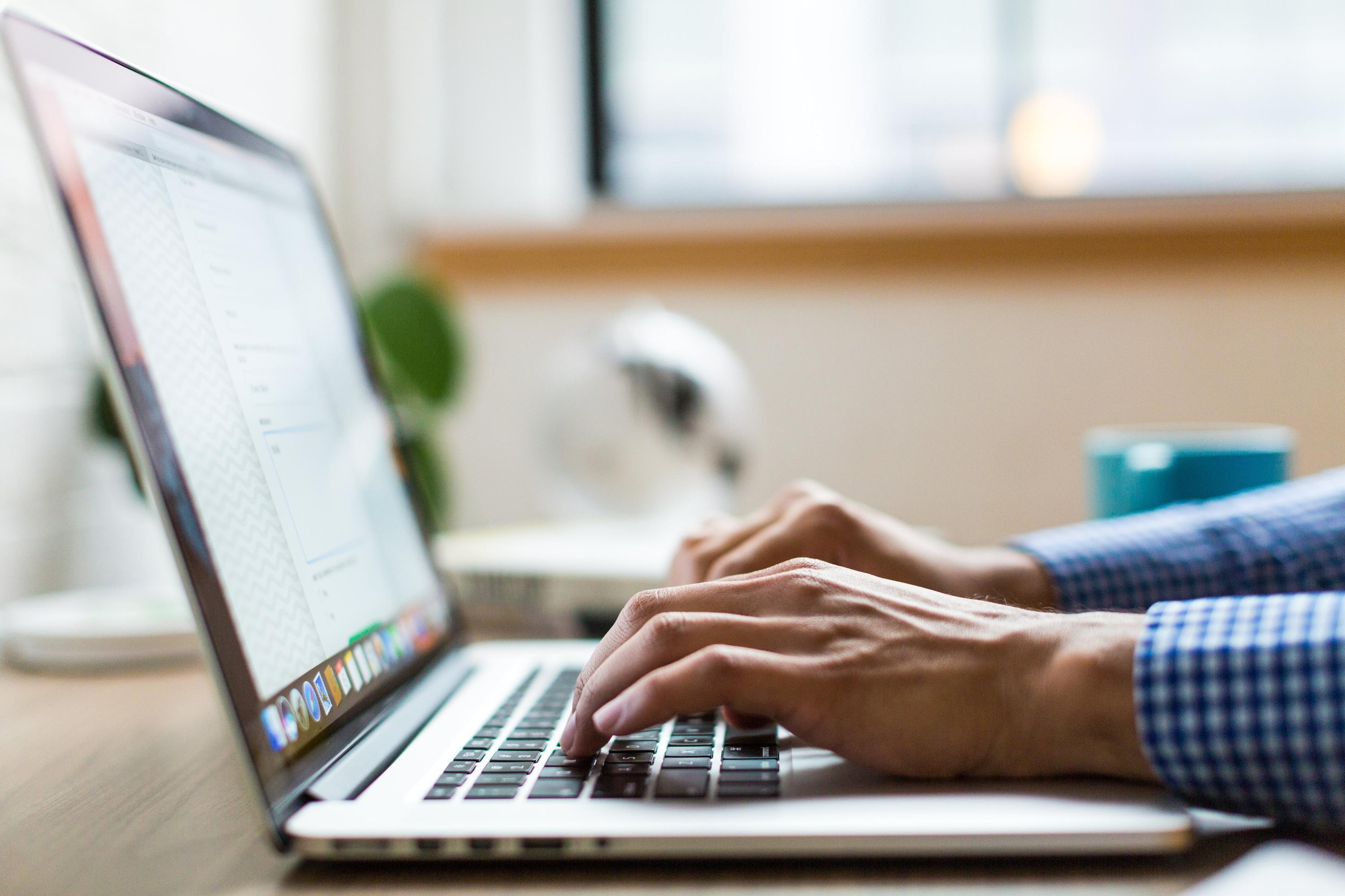 Person typing on a silver laptop