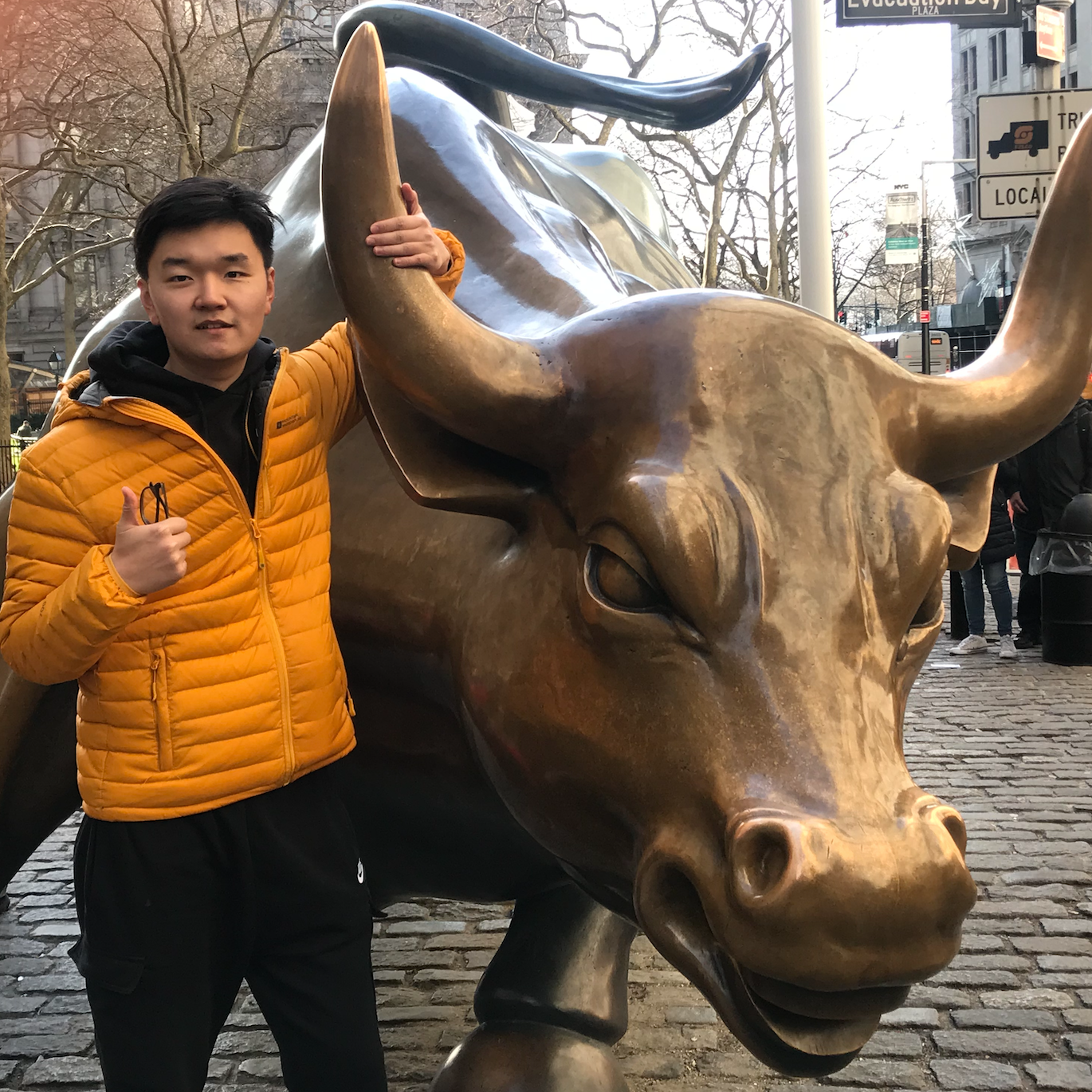 man with his thumb up standing beside a bull