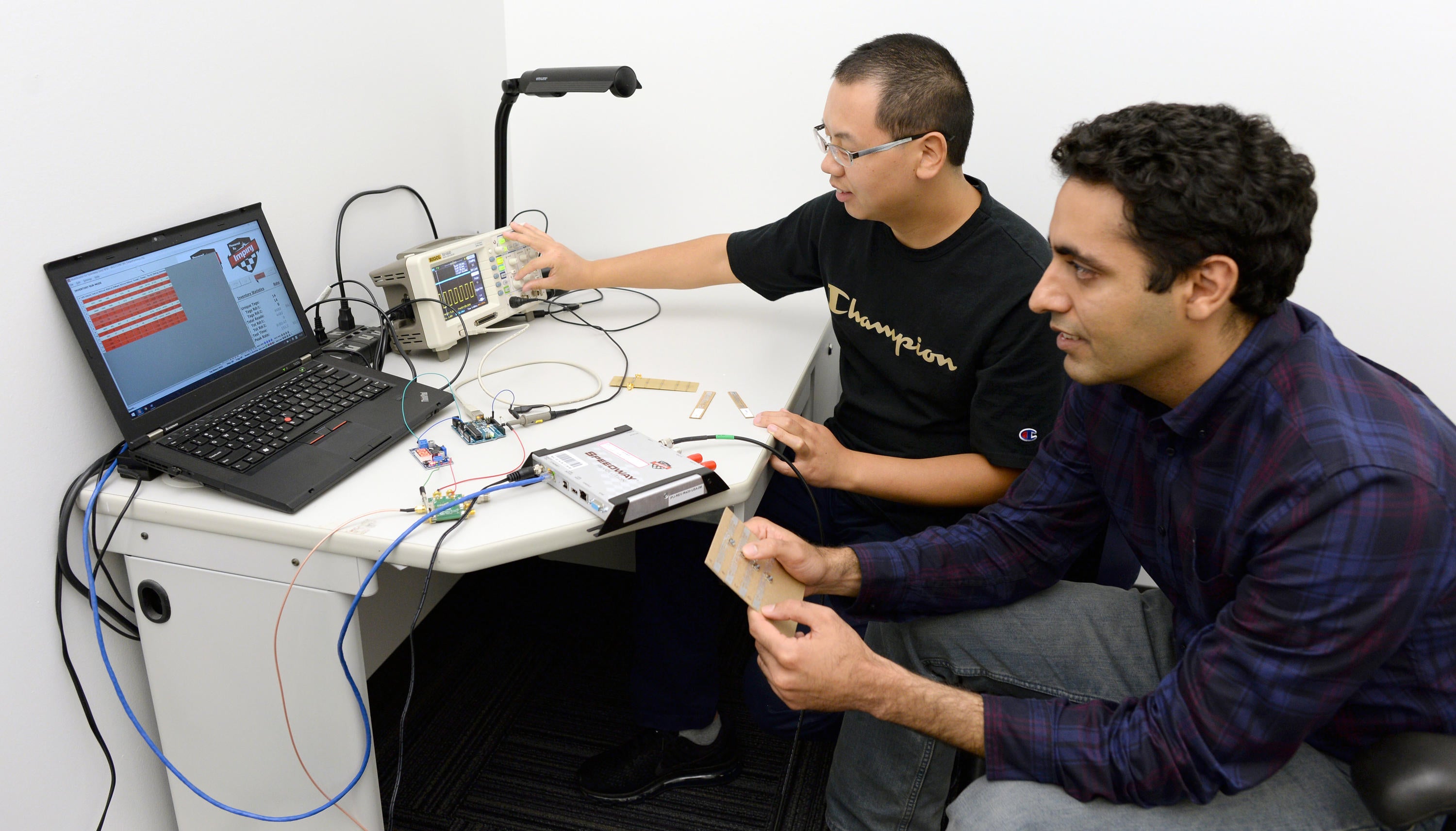 Ju Wang and Omid Abari demonstrate their device at a computer.