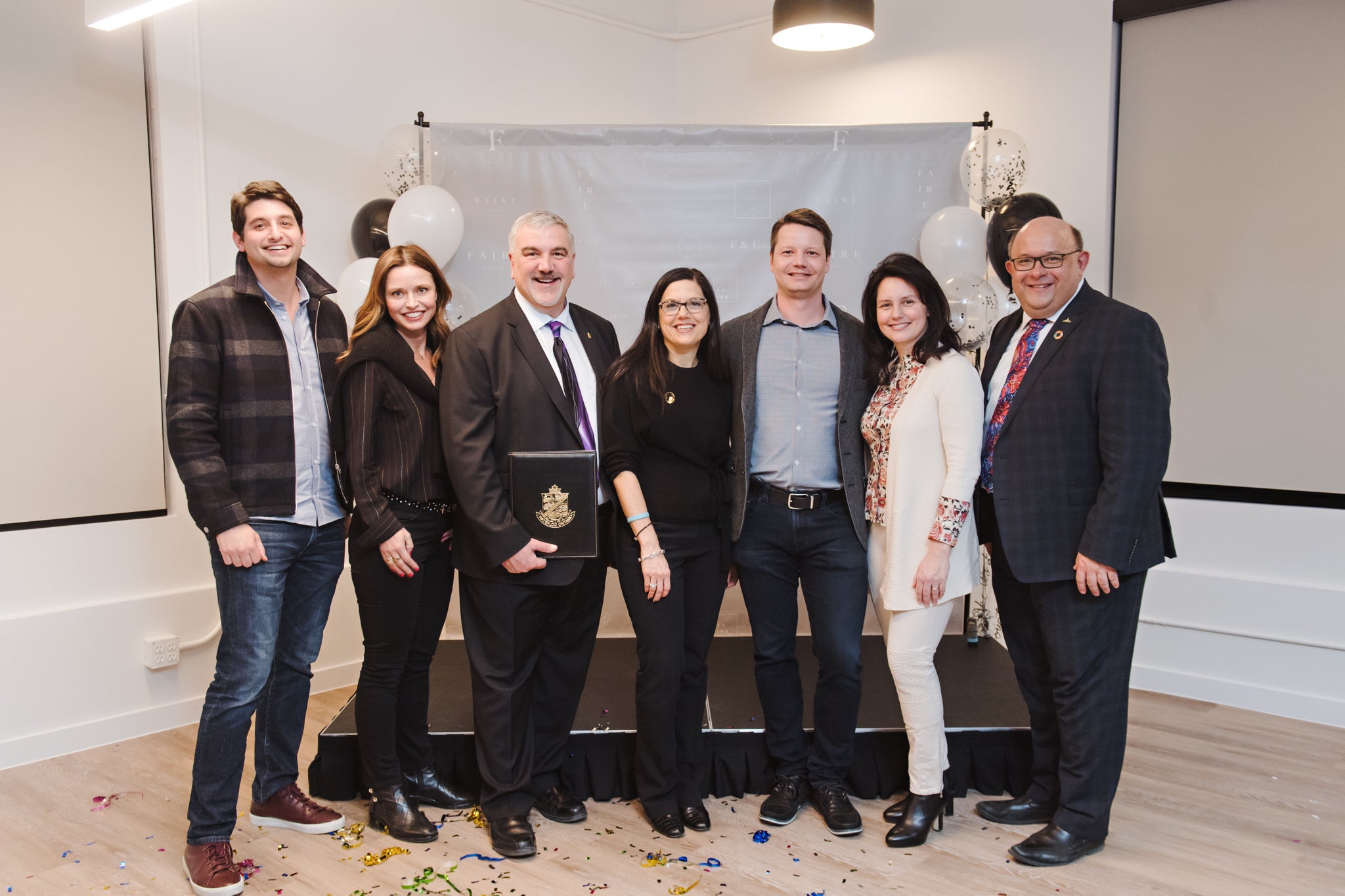 7 people standing side by side smiling posing for a picture