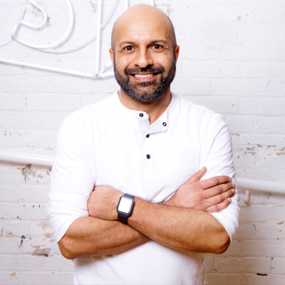 headshot of a man with a beard wearing a white top
