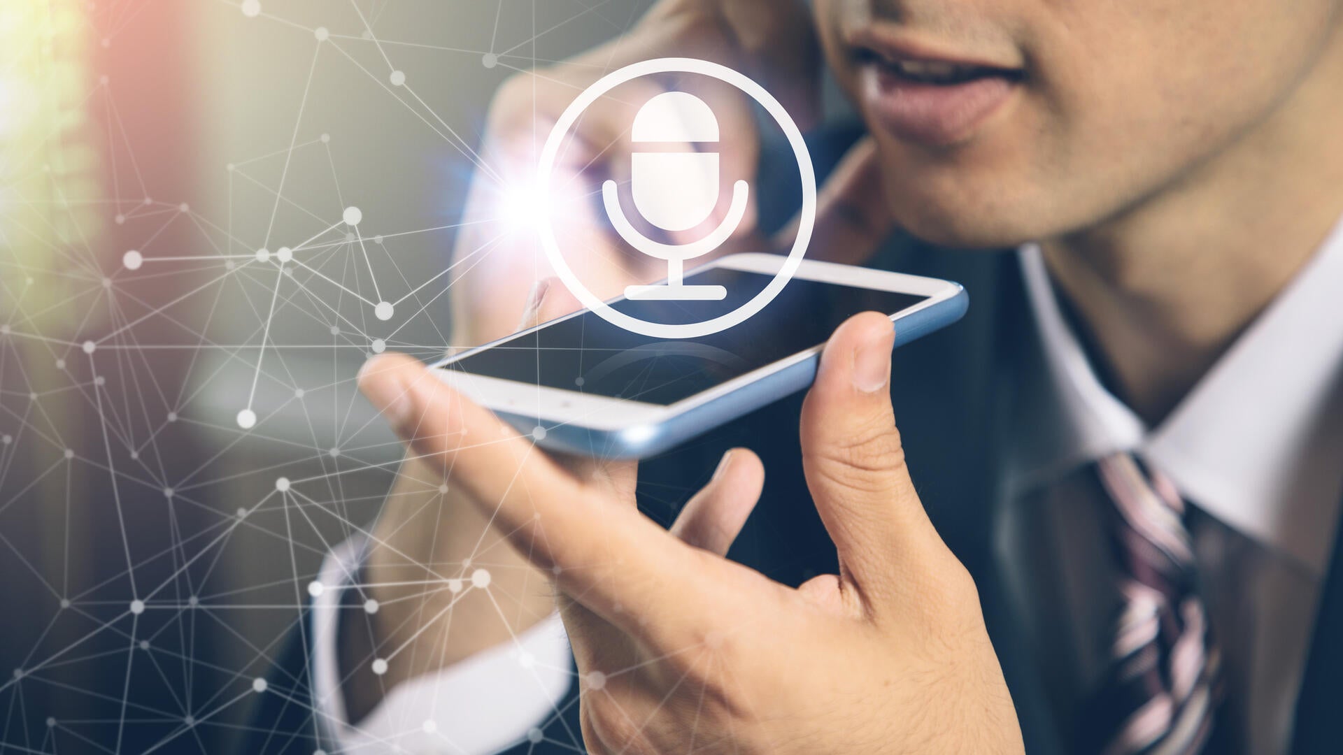 a man talks into a smart phone, which has a microphone icon superimposed over it