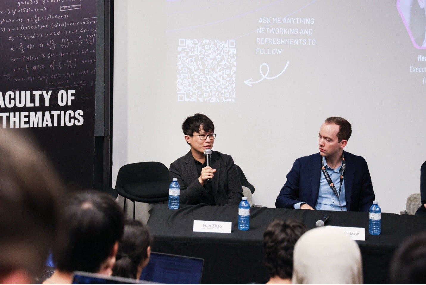 Han Zhao with the microphone in his hand at the panel discussion