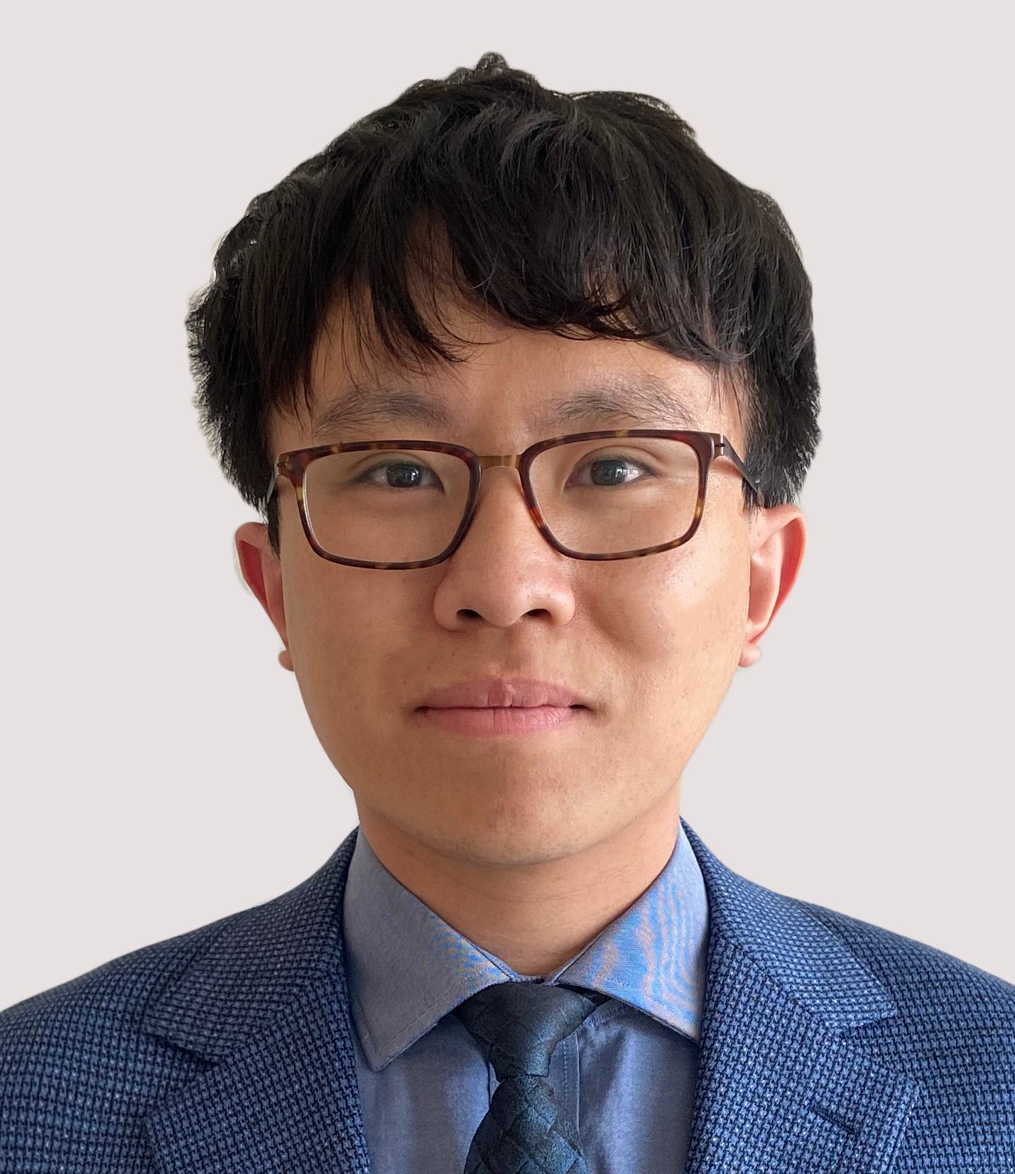 Headshot of man wearing glasses and a blue suit and tie