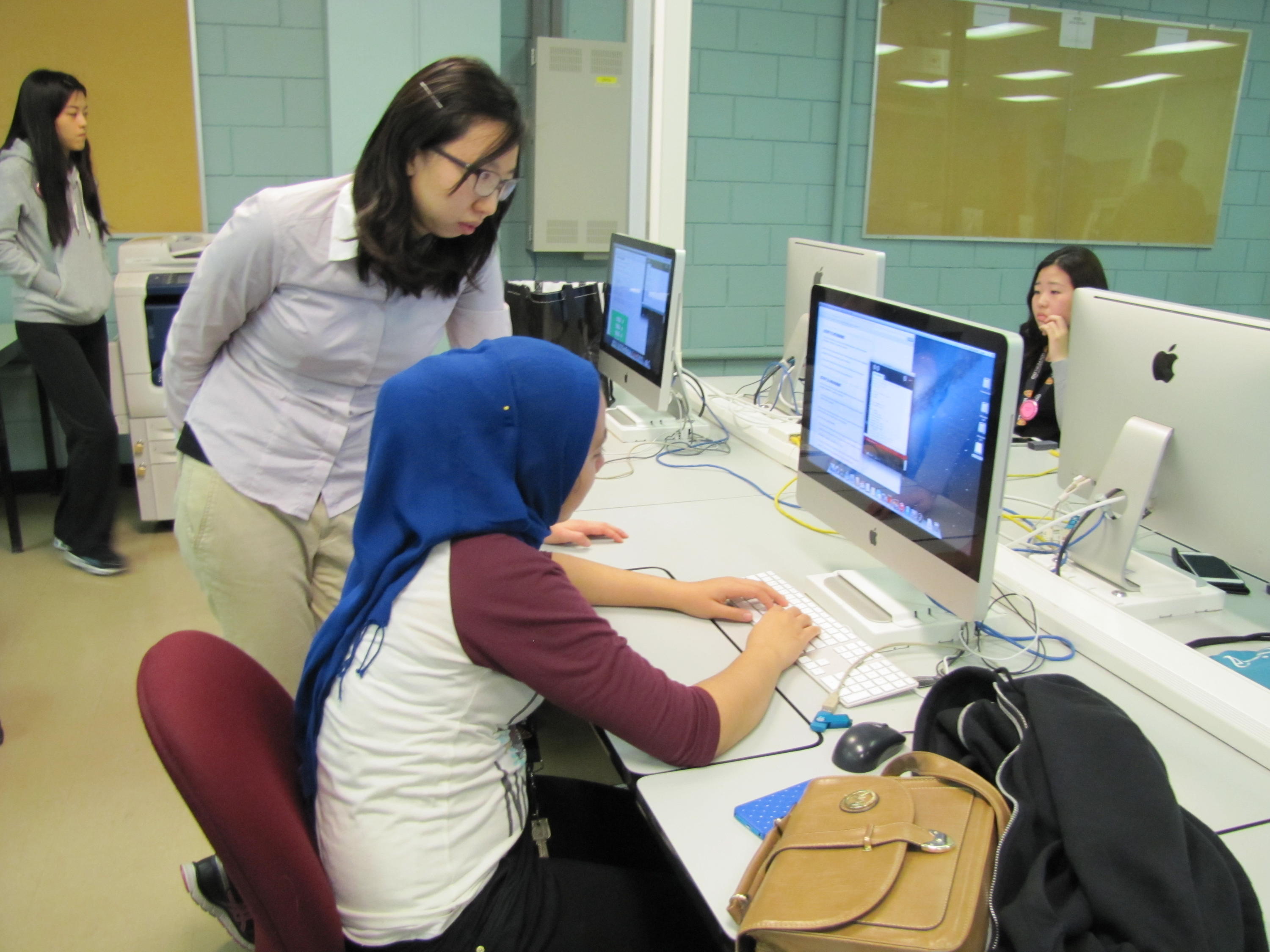 A teacher helps a student in a computer lab