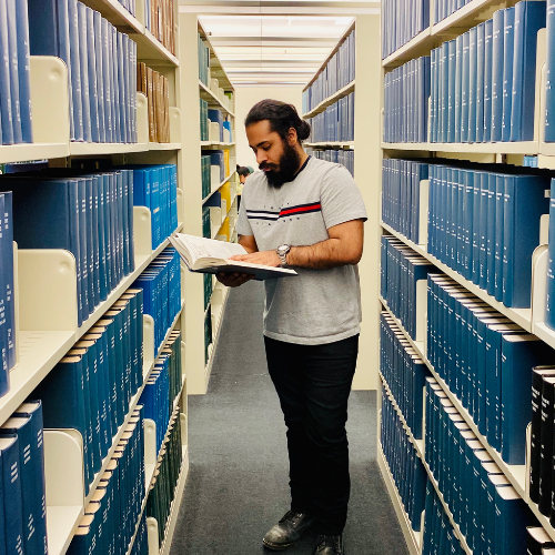 Photo of Jaskirat Bhatia looking at a book in a library