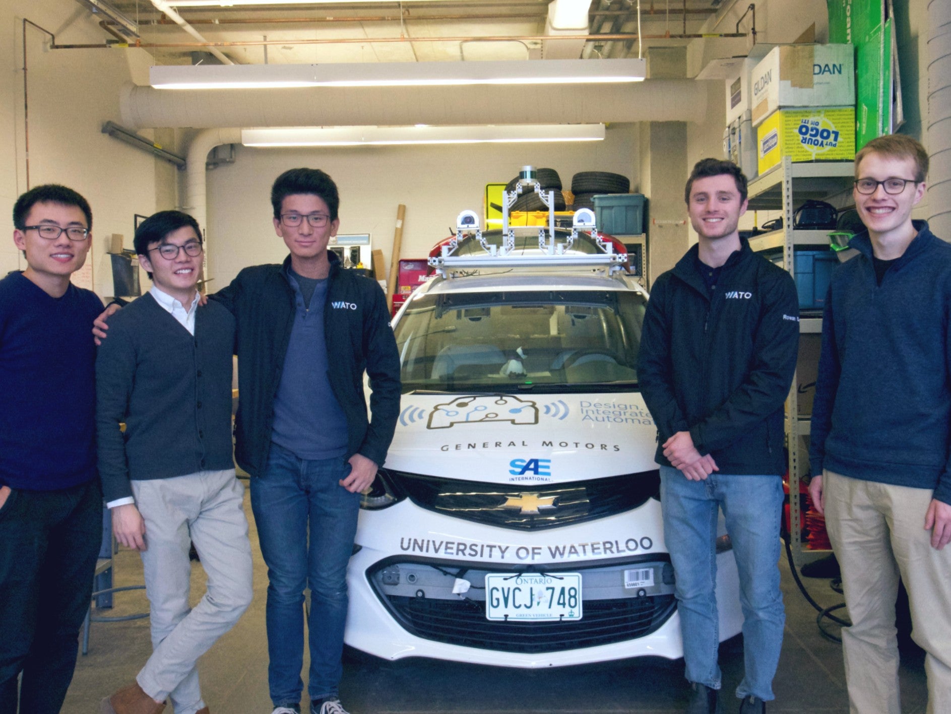 Five members of the WATonomous team stand in front of the vehicle