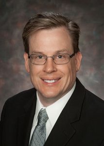Head shot of man with short business hair, glasses smiling