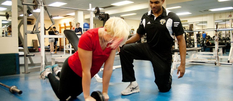 Personal trainer leading a student in a workout.