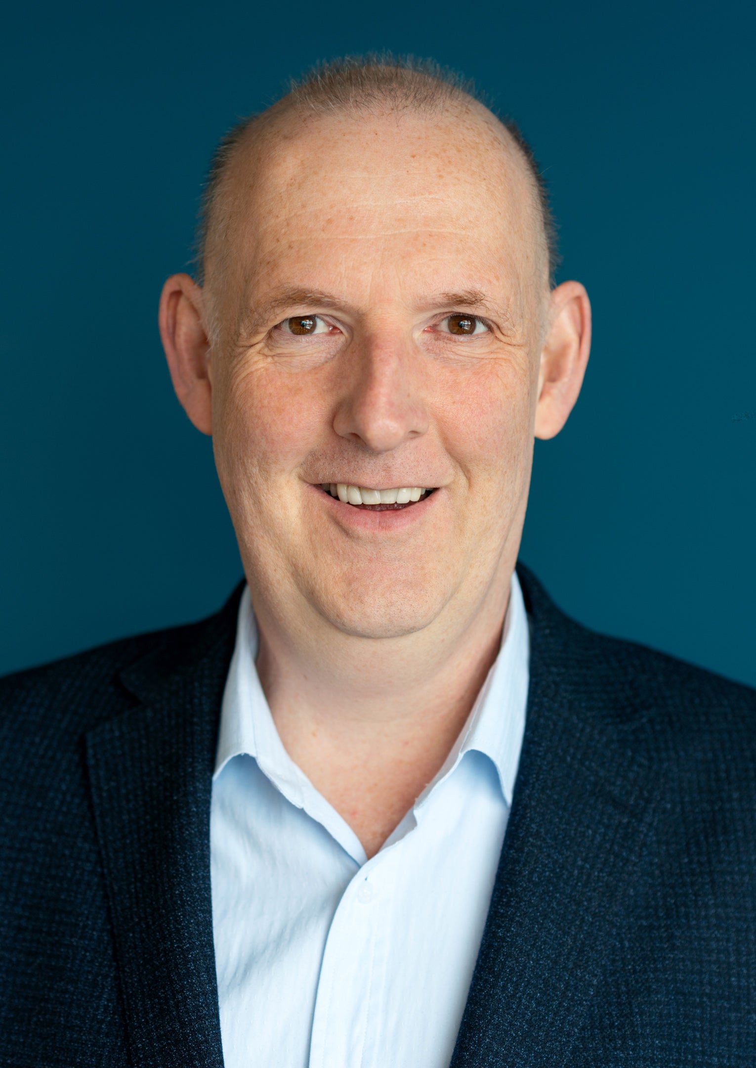 headshot of a man wearing a blue dress shirt and jacket