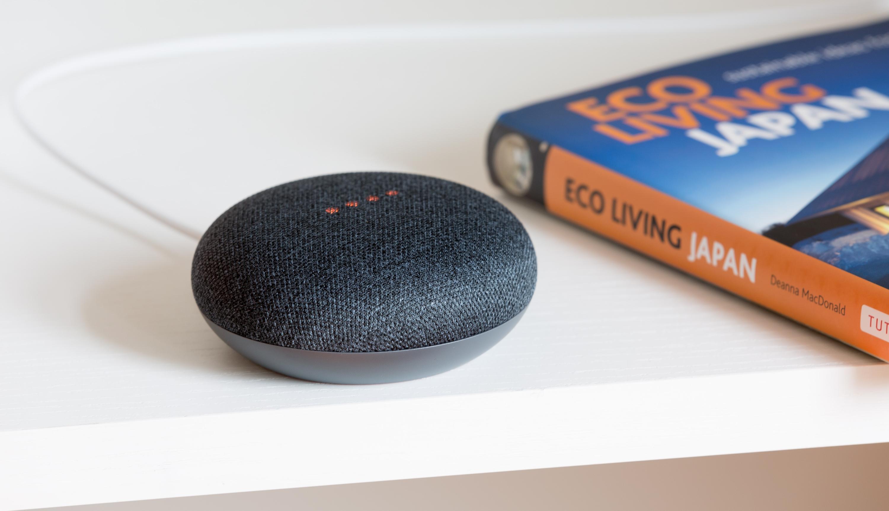 A Google Home Mini virtual assistant sits on a shelf