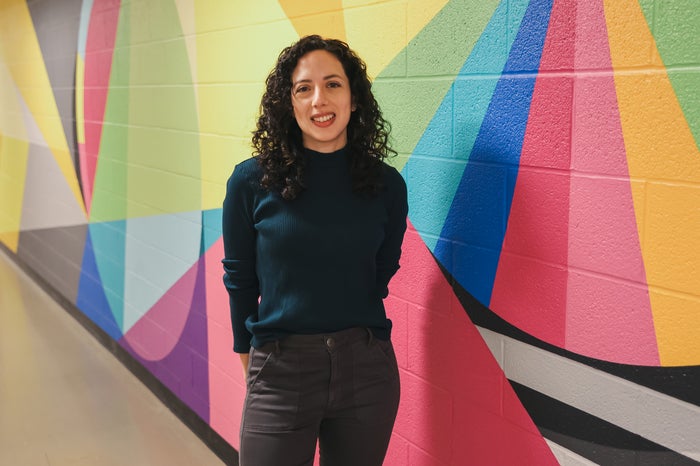 Stephanie stands in front of a colourful mural 