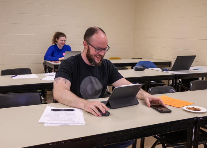 A person smiles while grading on a tablet