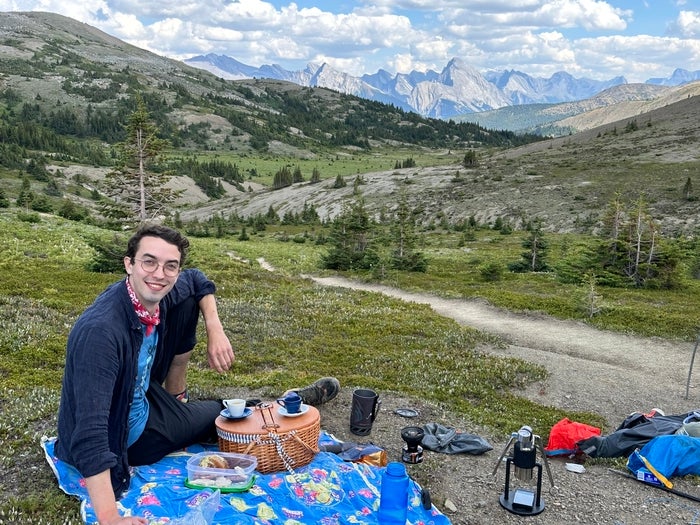 Jacob sits on a picnic blanket in front of mountains