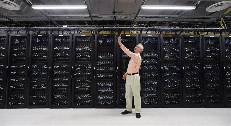 Man takes selfie in front of wall of supercomputer servers