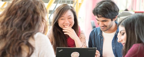 Students working together on a laptop, smiling