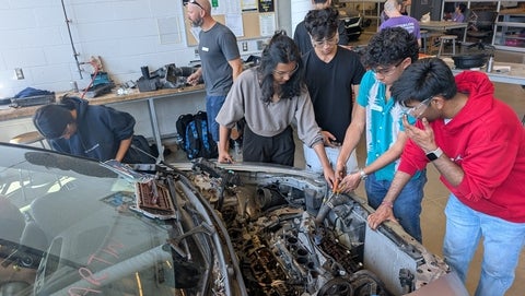 Students dissecting a car's engine bay