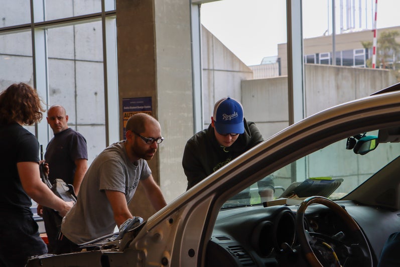 Student and staff member working under the hood of the car