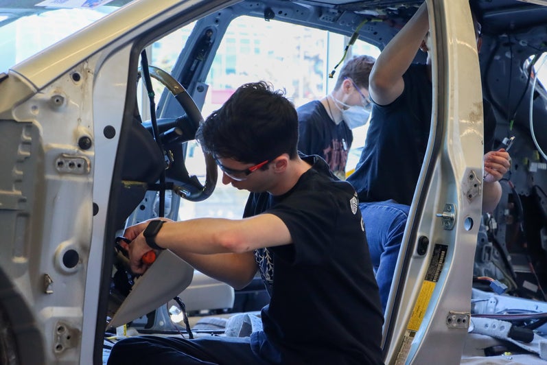 Student working at the steering column of a car