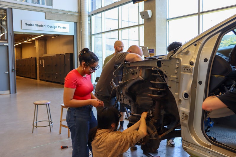 Students working at the wheels of a car