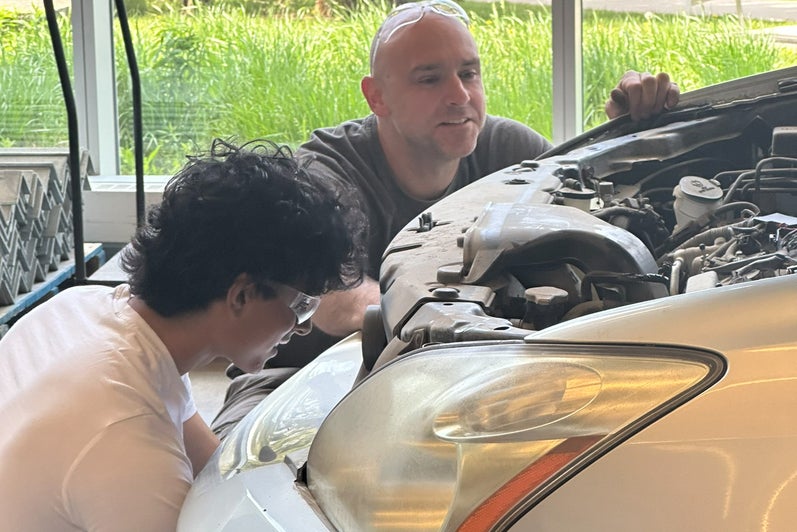 Student and staff member working on car