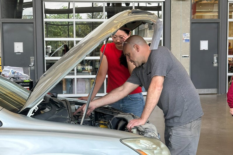 Student and staff member working on car