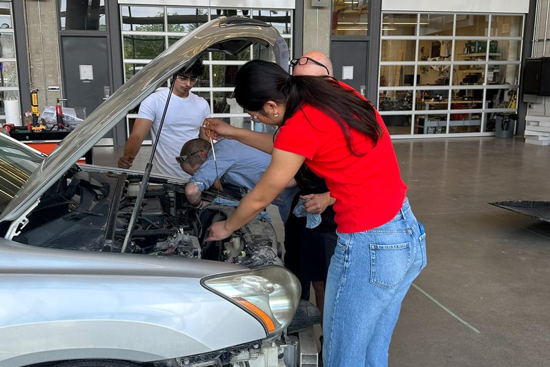 Students and staff members working to under the hood of the car