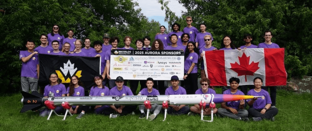 Waterloo Rocketry team with holding up sponsorship sign and standing behind their liquid rocket