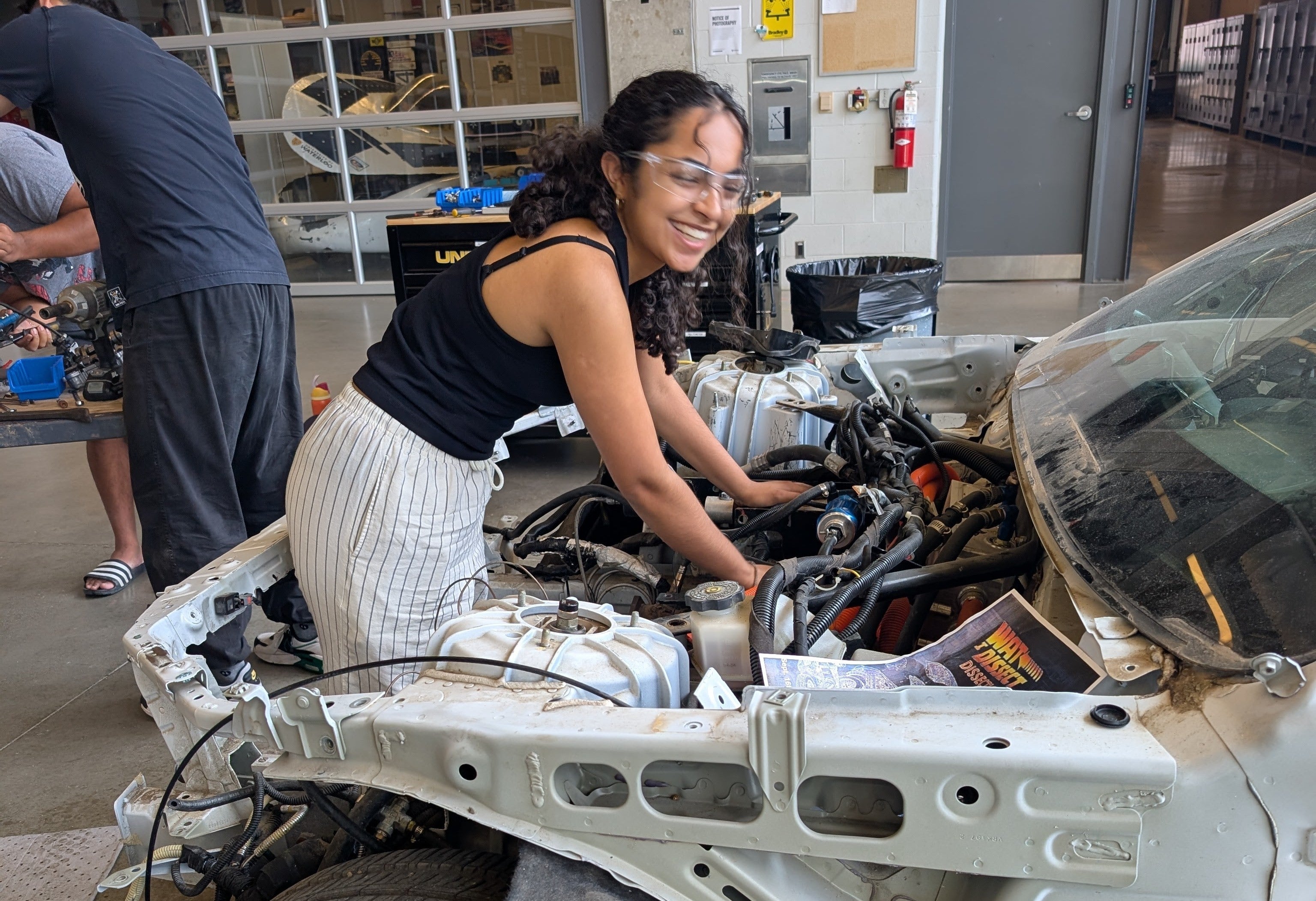 Student in an engine bay taking parts out