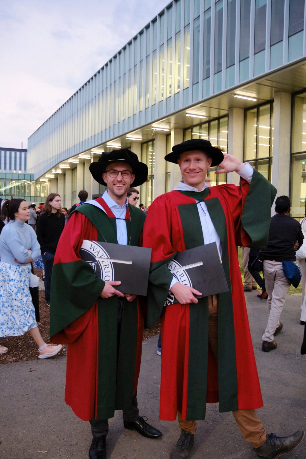 PhD graduates posing with their degrees in their red and green regalia. 
