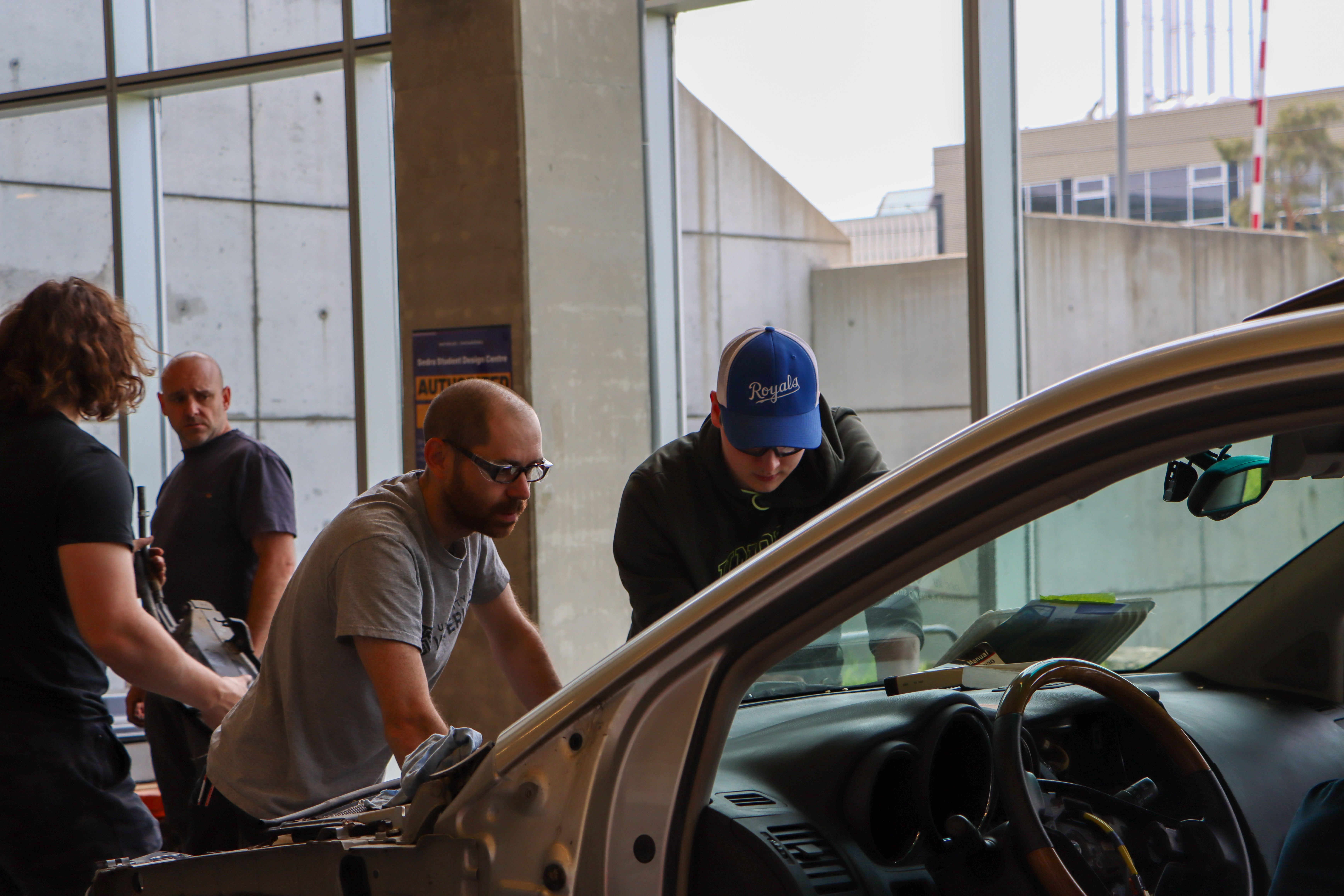 Student and staff member working under the hood of the car