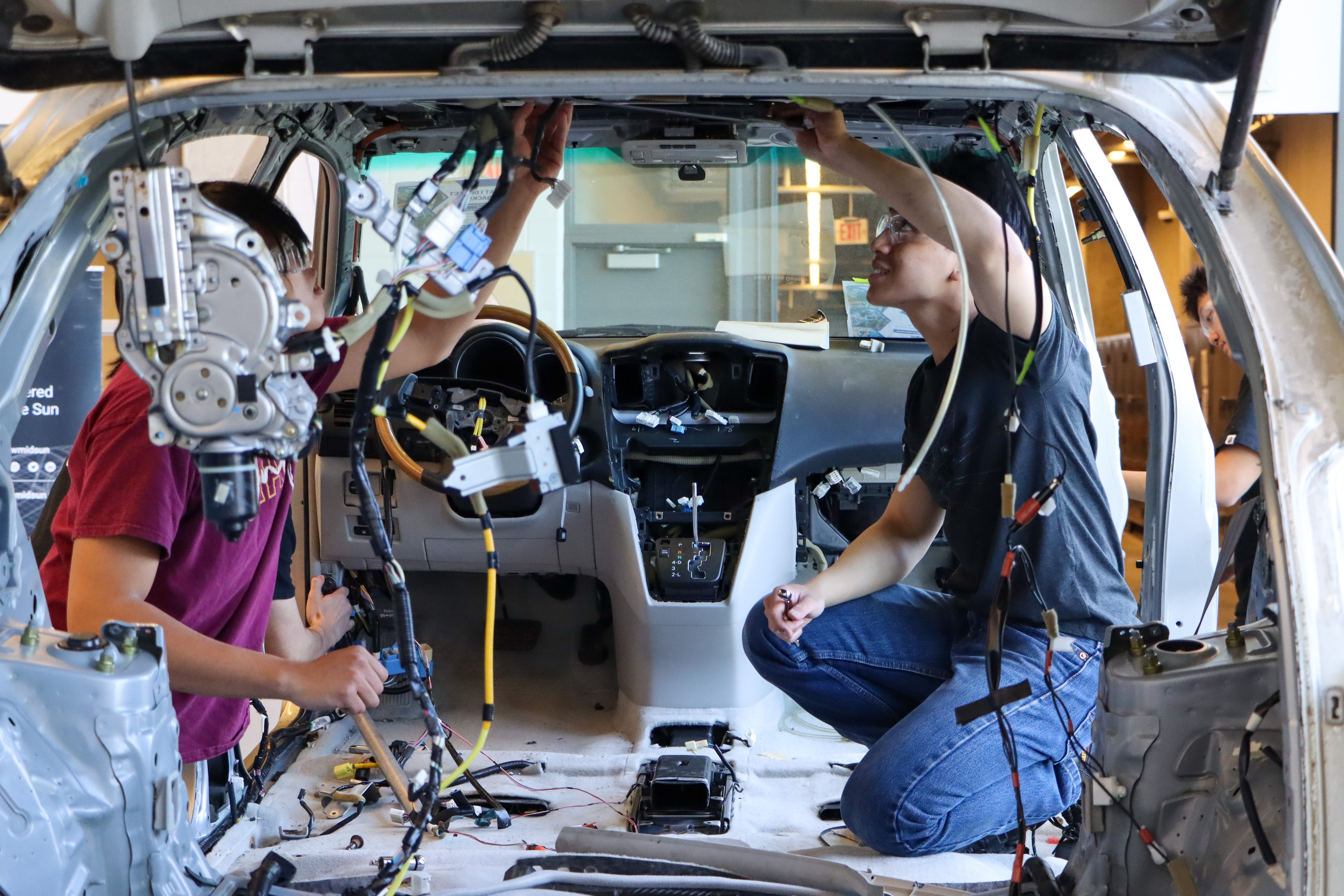 Students taking apart the interior of a car