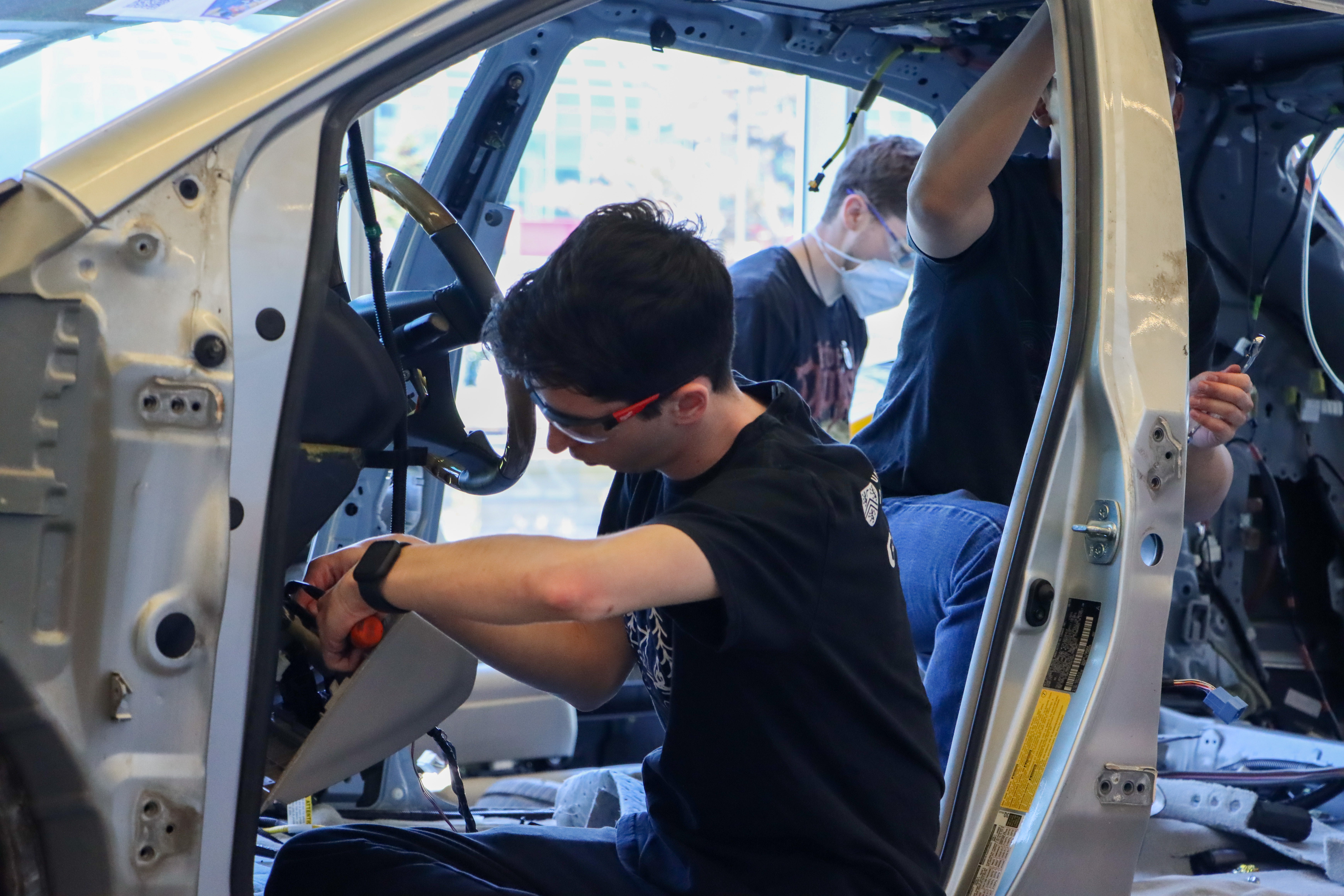 Student working at the steering column of a car