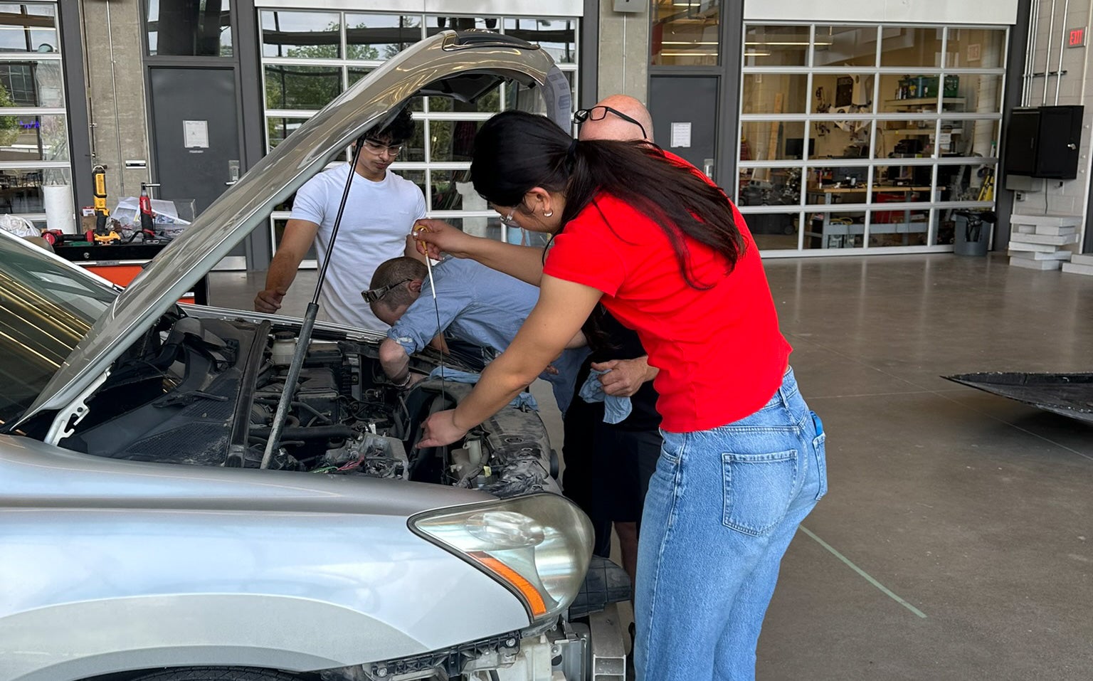Students and staff members working to under the hood of the car