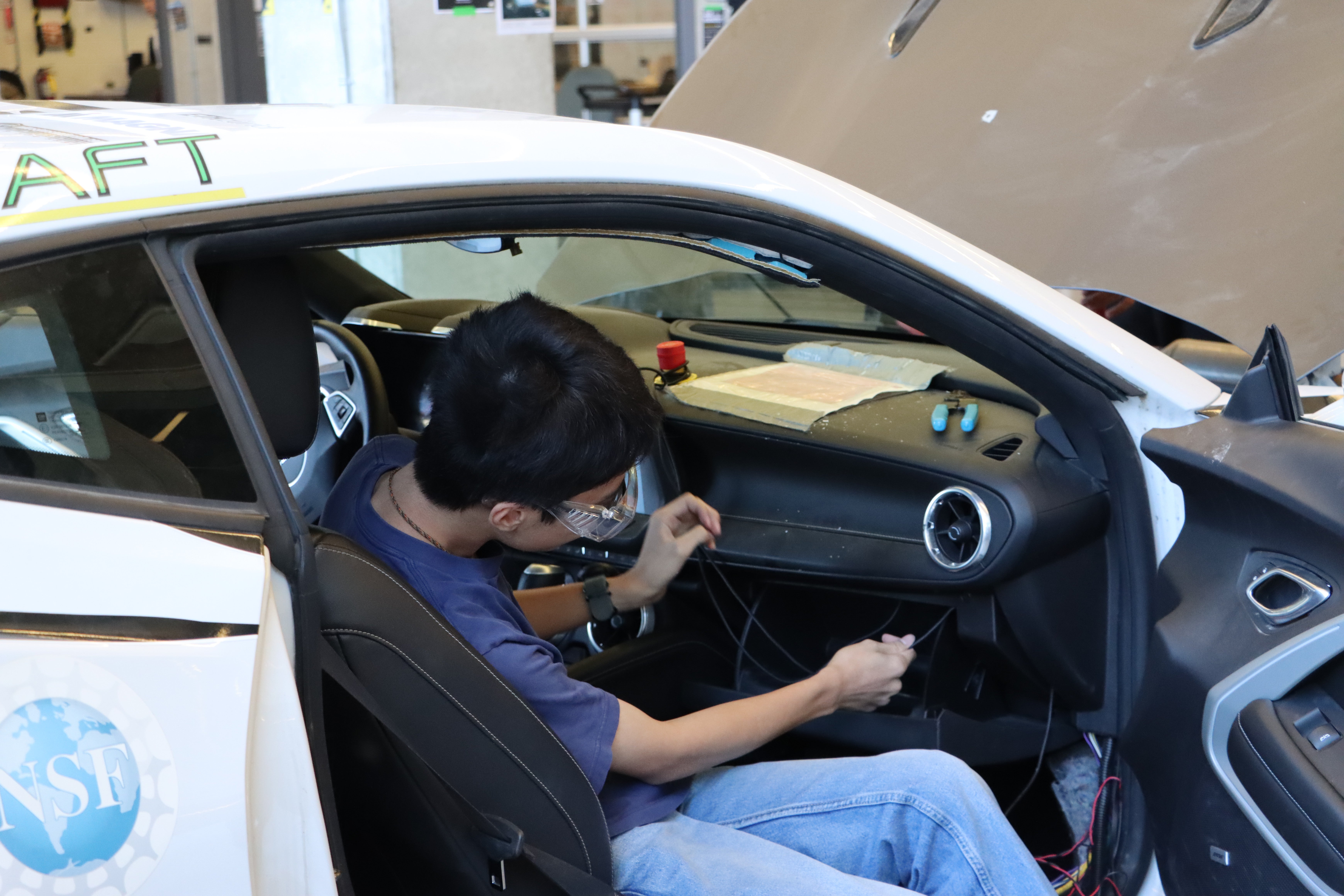 Student taking apart the interior of a car