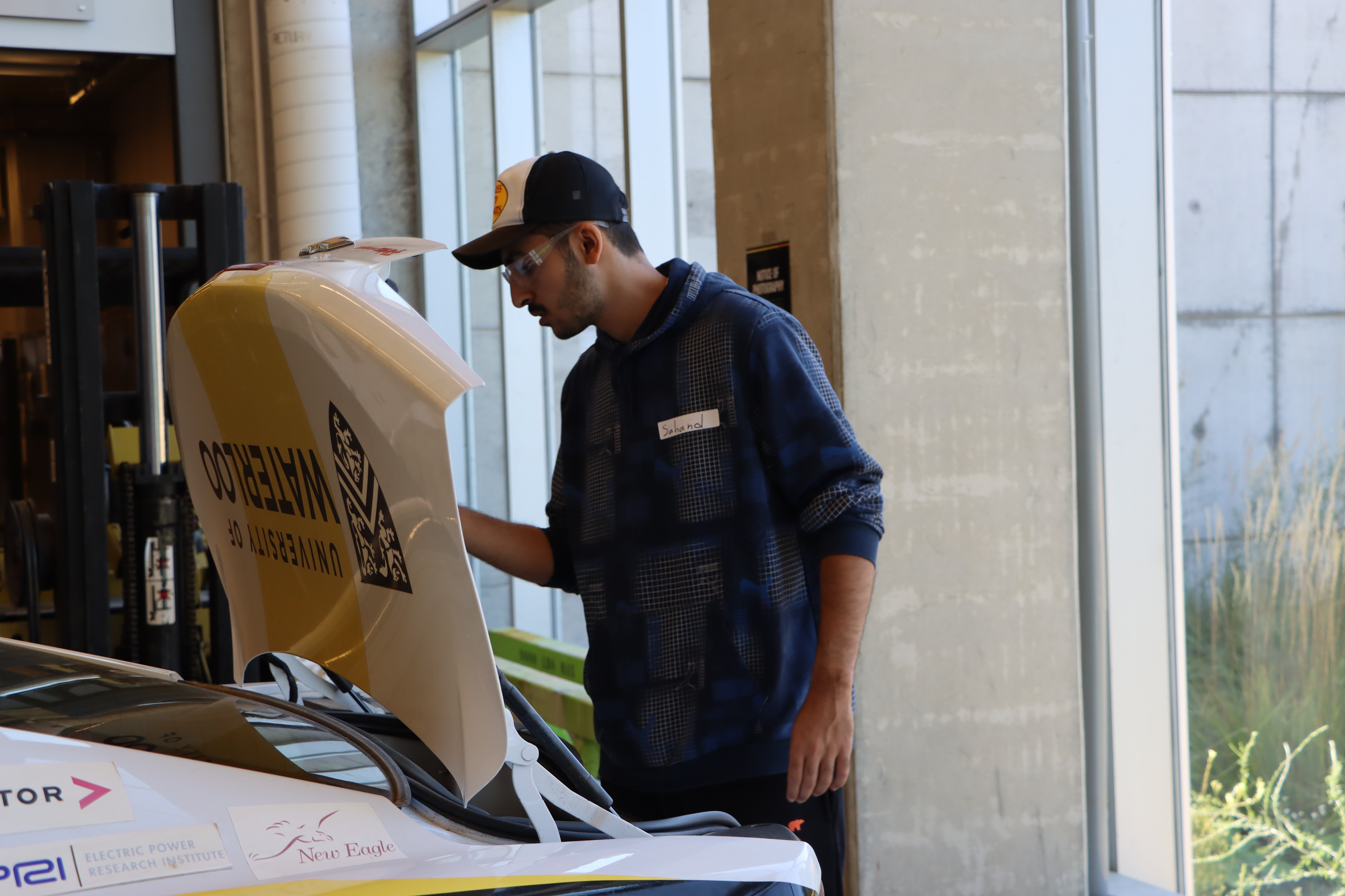 Student examining trunk door of a car. 