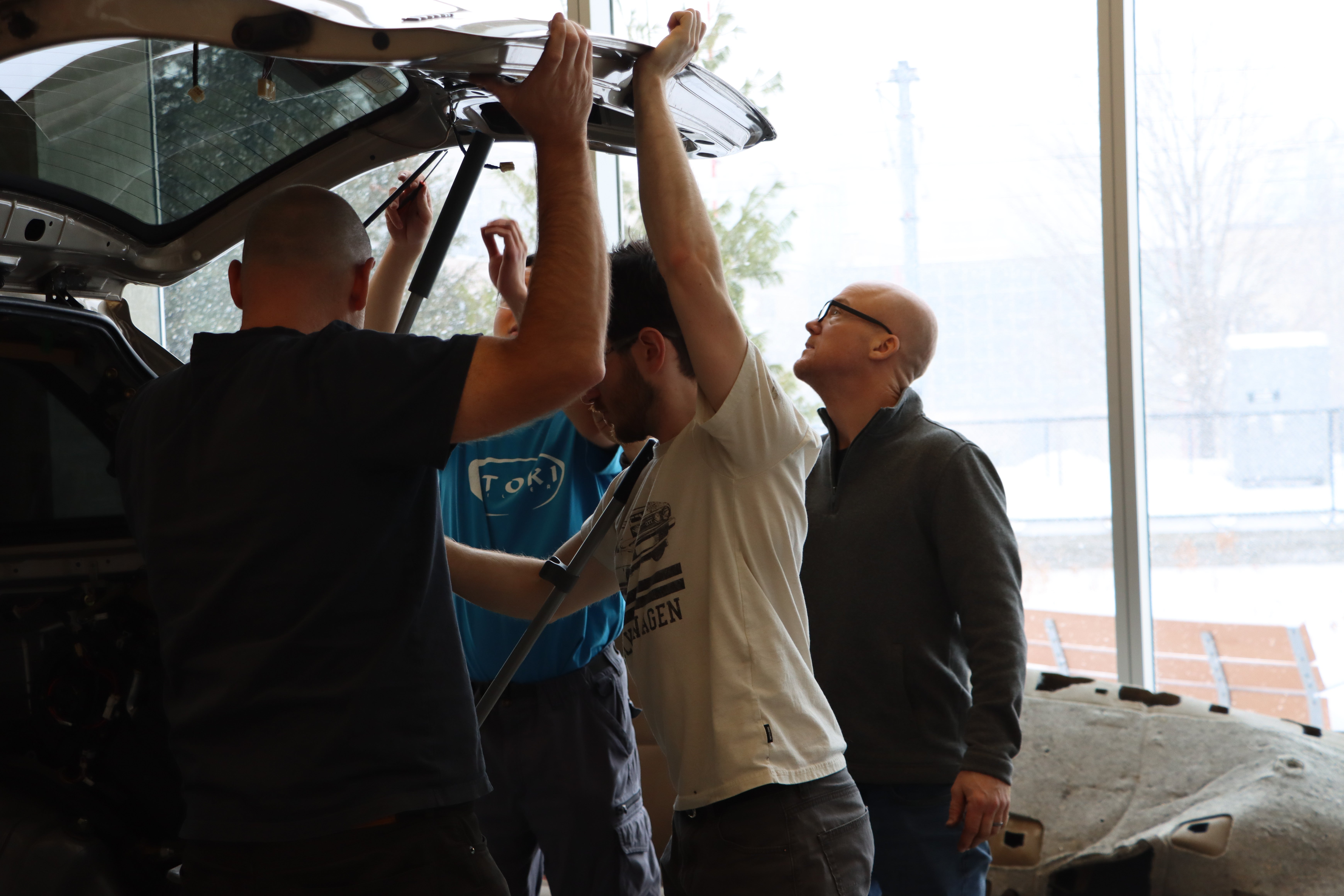Students taking off the trunk door of a minivan. 