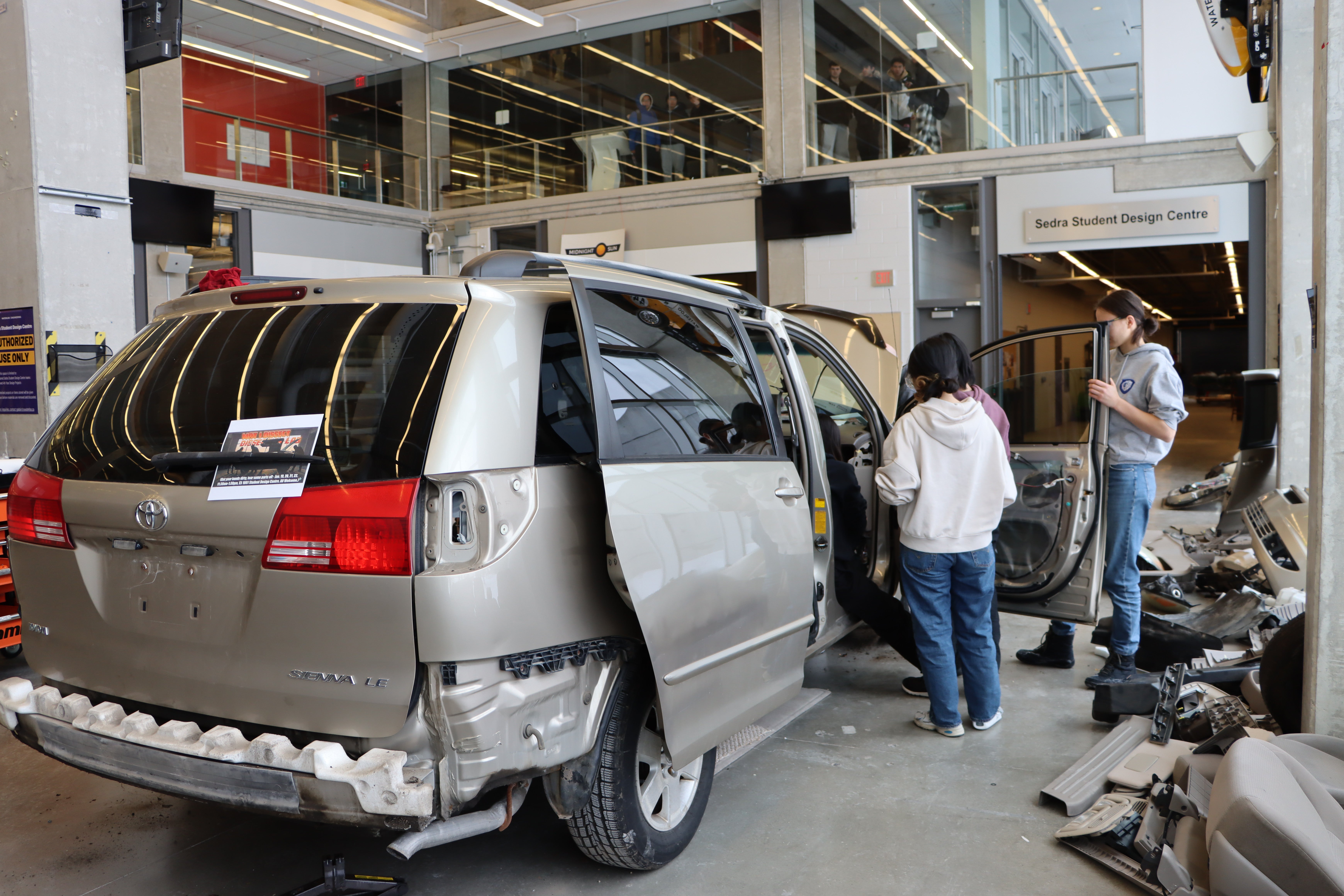 Students examining the parts of a minivan. 