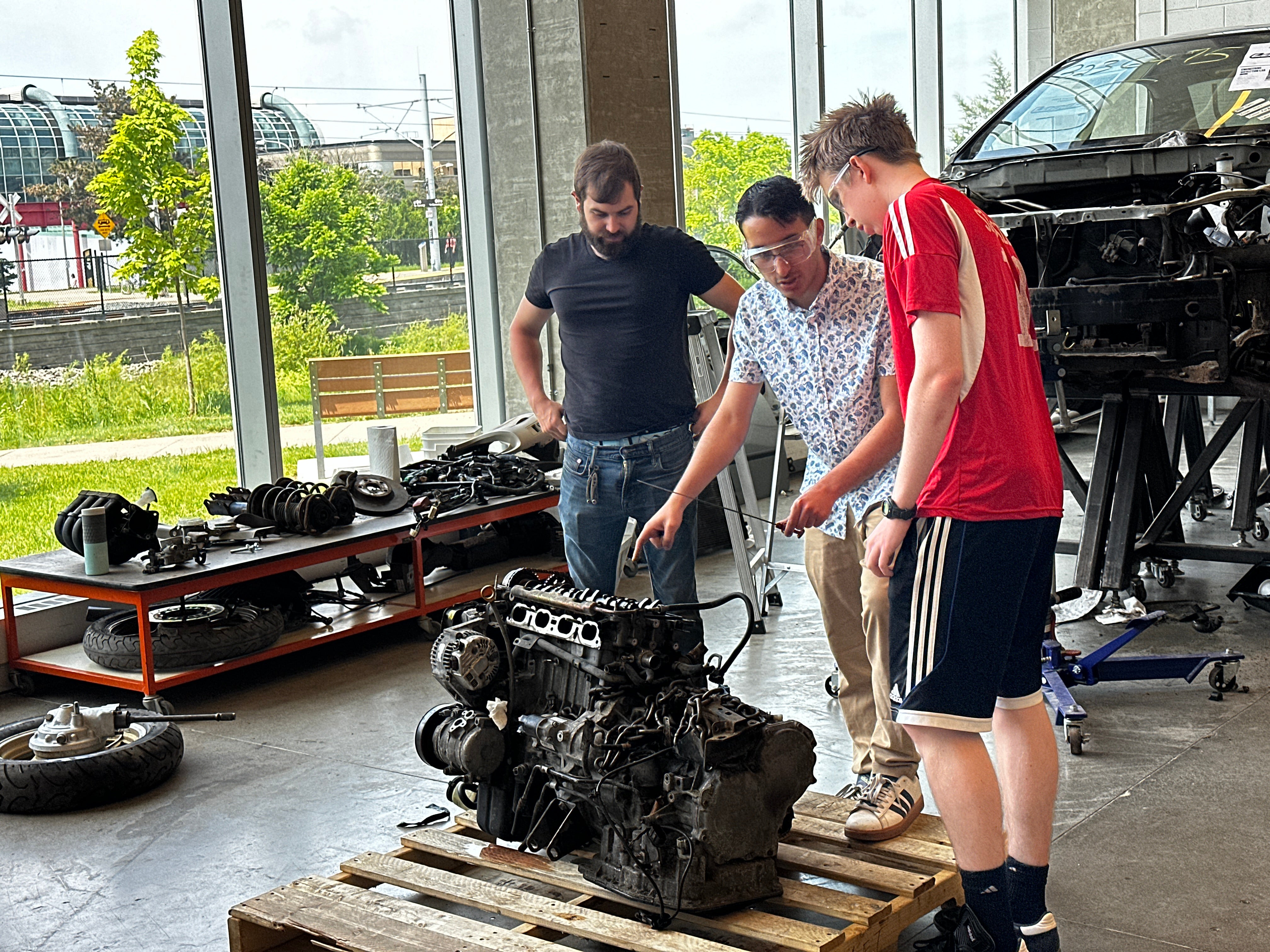 Students examining a car engine 