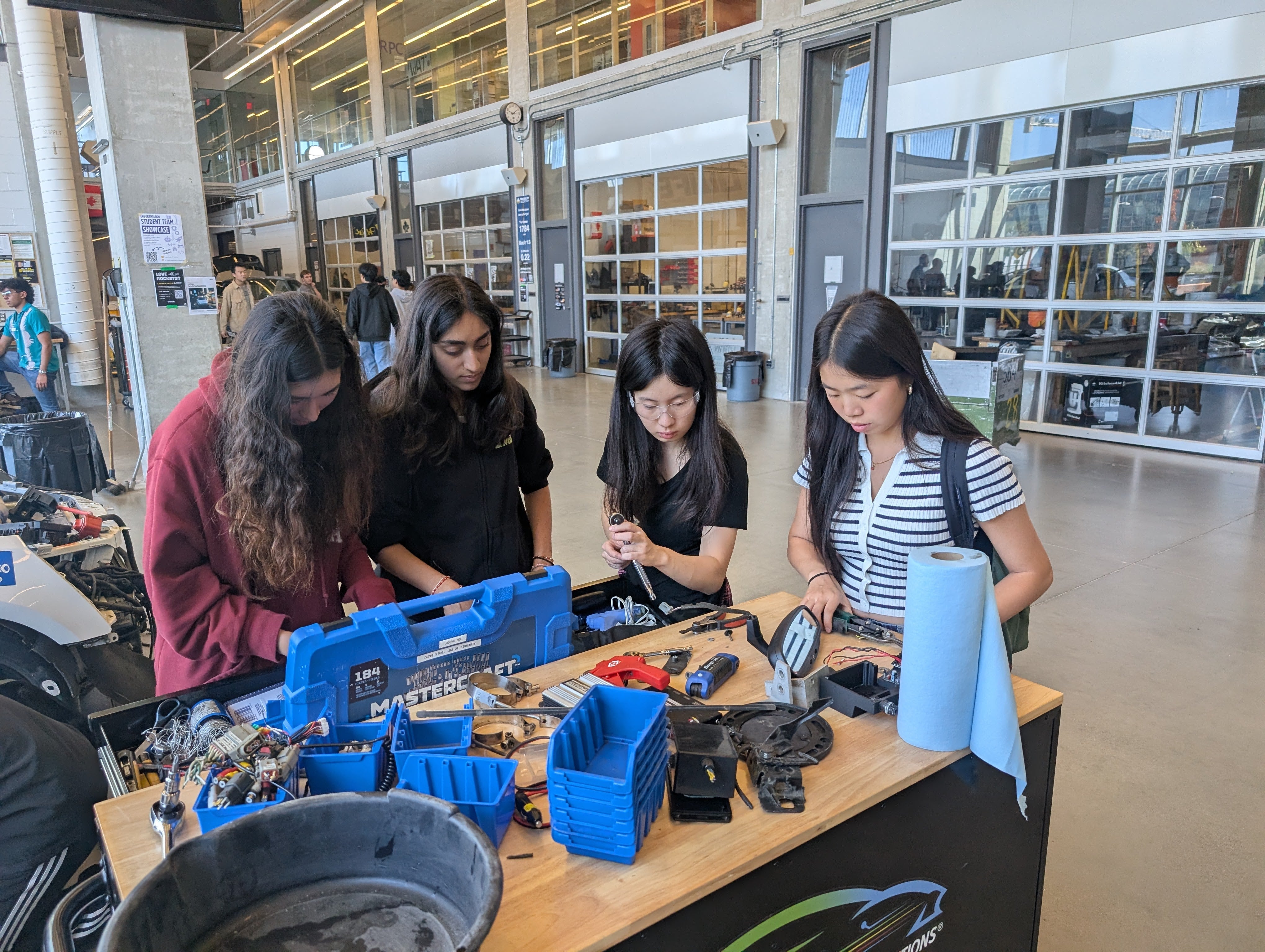 Group of students grabbing tools for car dissection