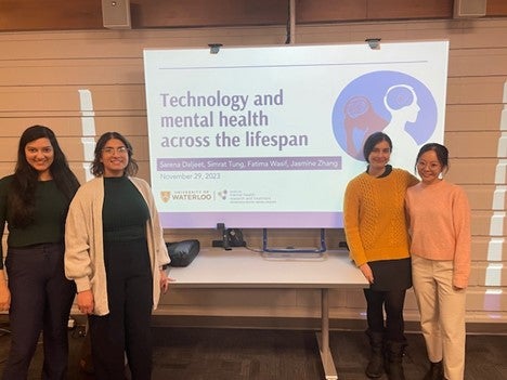 Four students presenting in front of screen. Left to right: Sarena Daljeet, Sim Tung, Fatima Wasif, and Jasmine Zhang.