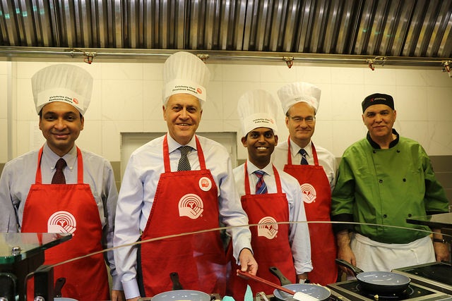 Sushanta Mitra and other faculty dressed as chefs behind a cooking line.