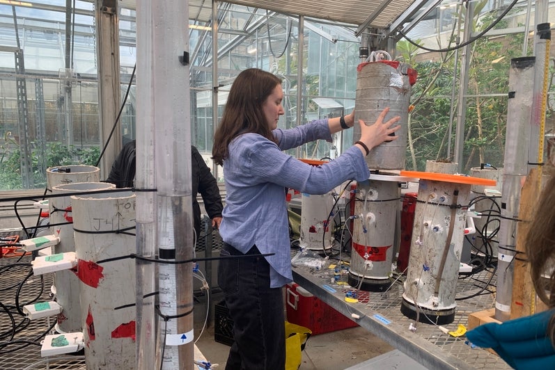 Post-doc Miranda Hunter places a methane flux gas chamber on top of a soil column to demonstrate how measurements are taken. 