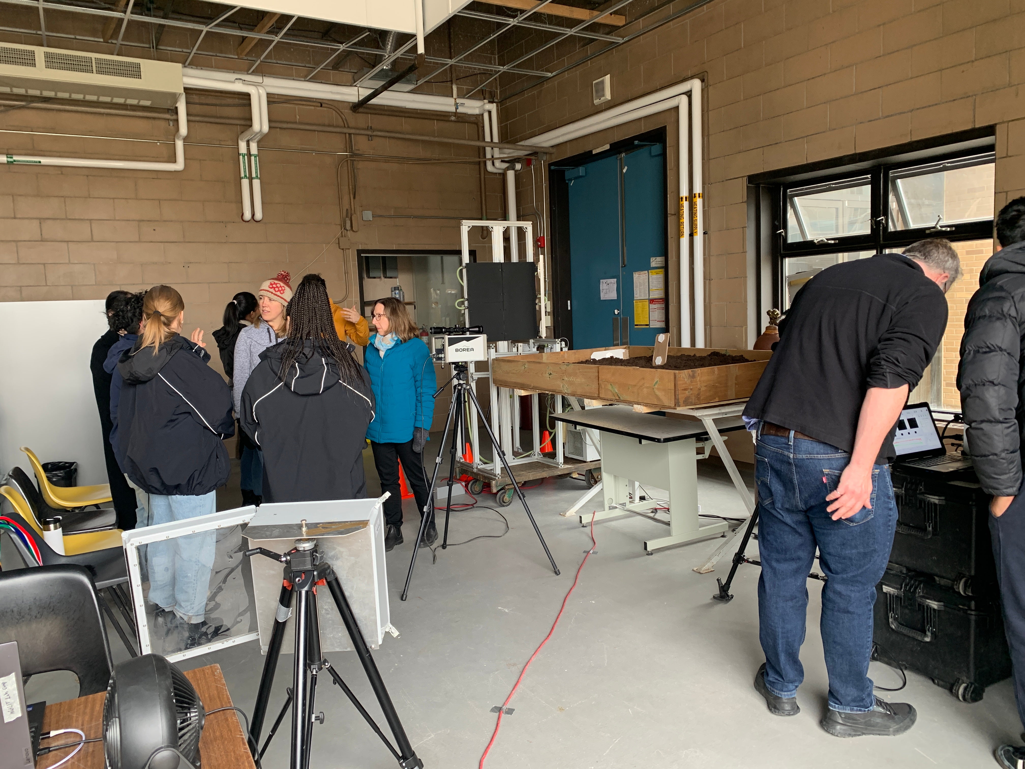 Participants huddle around the hyperspectral camera and TDLAS system. 