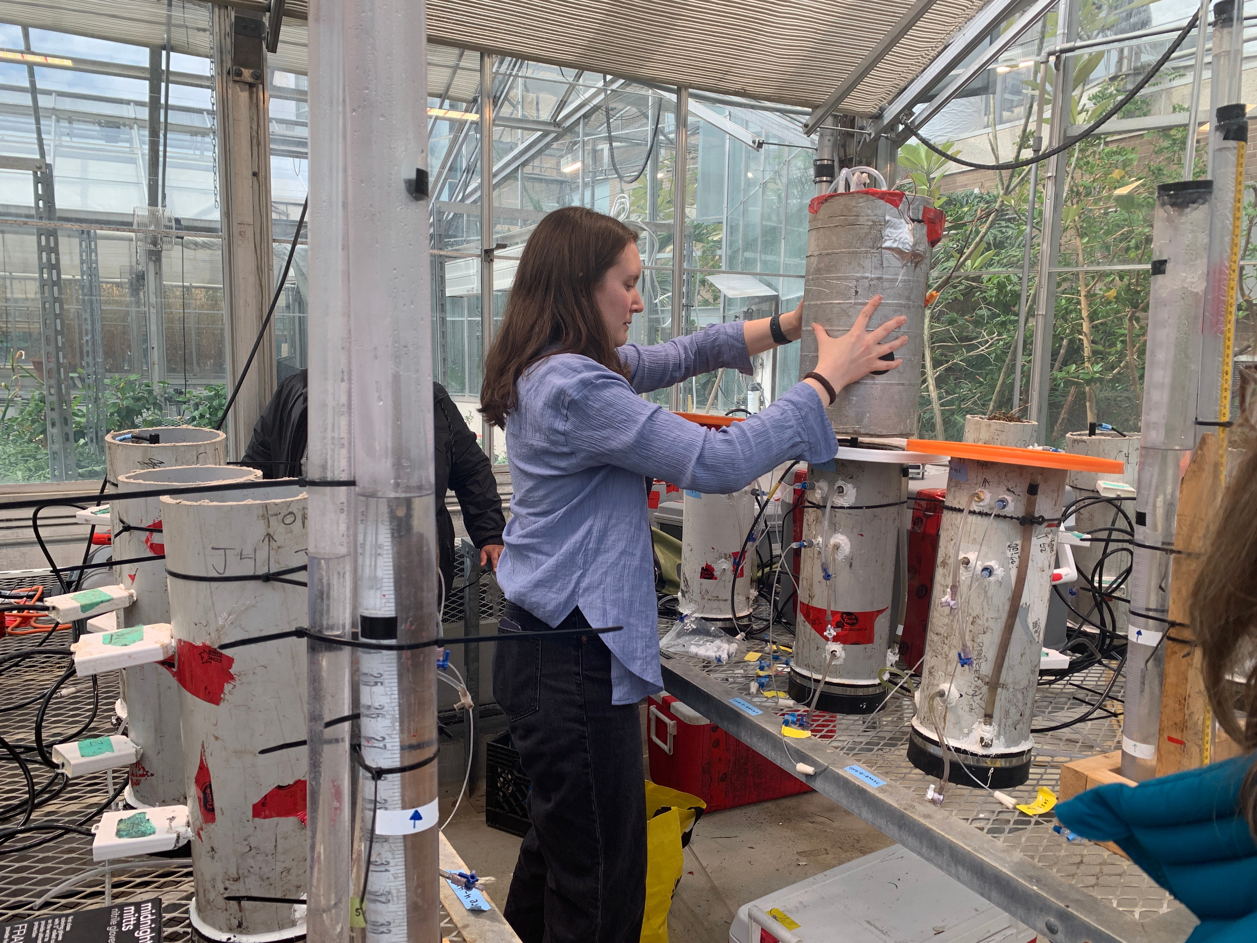 Post-doc Miranda Hunter places a methane flux gas chamber on top of a soil column to demonstrate how measurements are taken. 