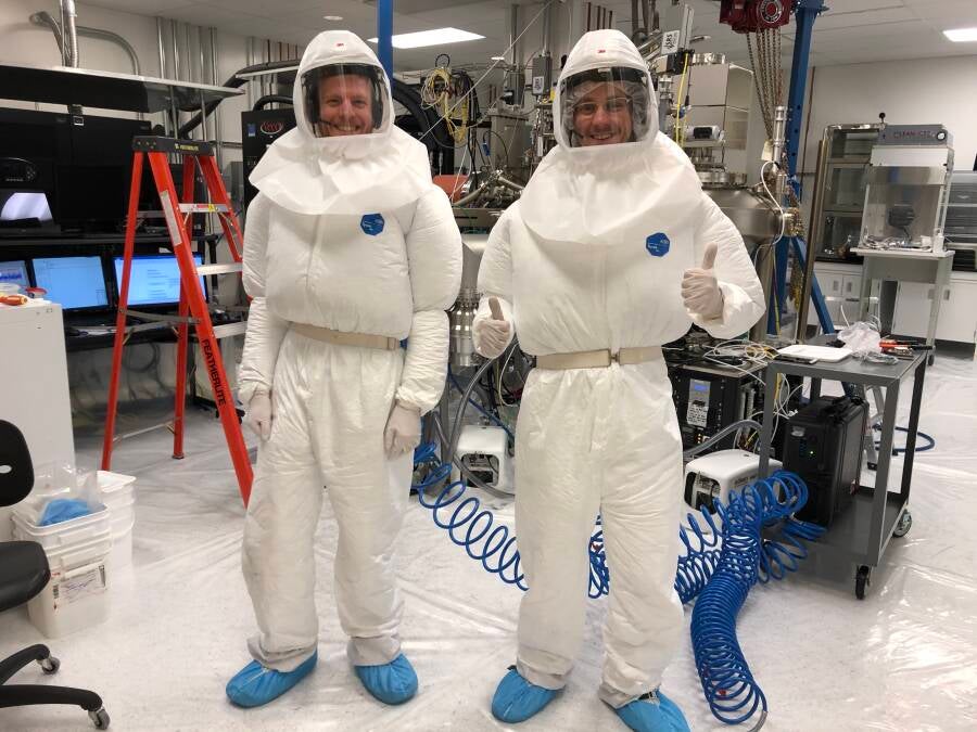 Two students wearing bunny suits and respirators in the lab