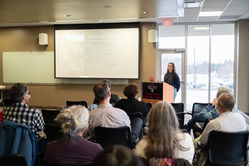 Madelynne Parish presenting at a podium to a group of people 