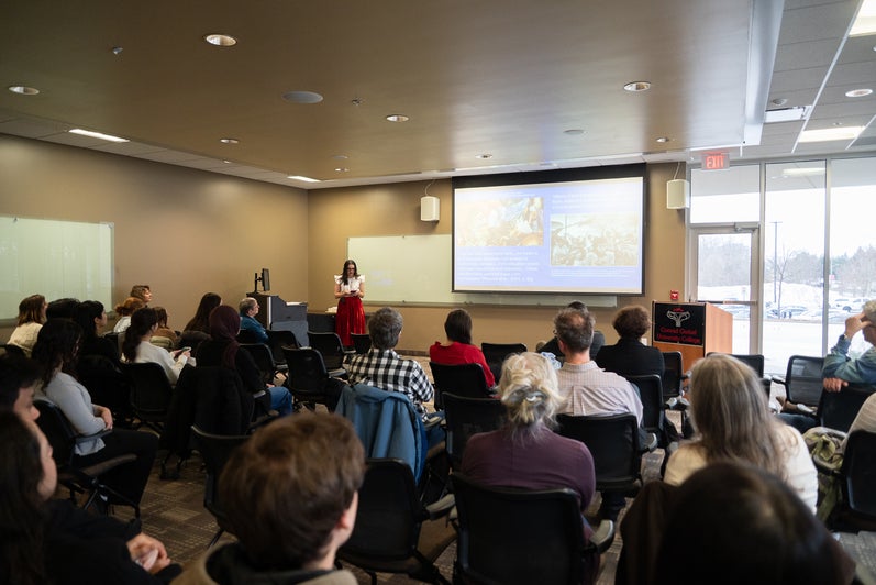 Anjelina Ramirez-Biggar presenting on projector screen in front of a crowd