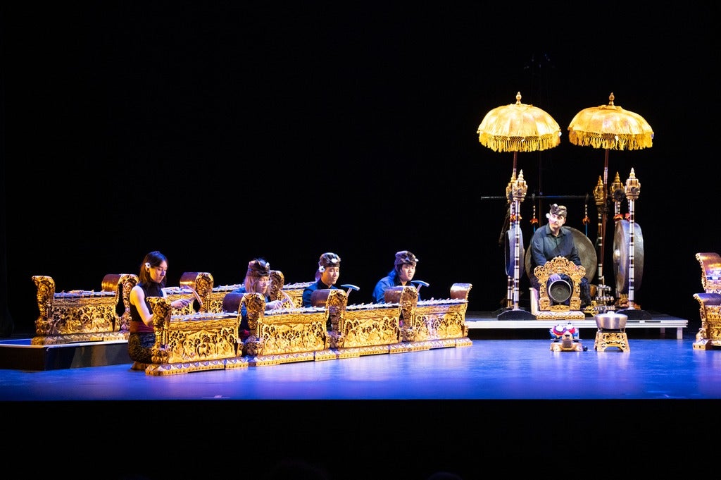 Balinese Gamelan players and instruments on stage lit in blue light
