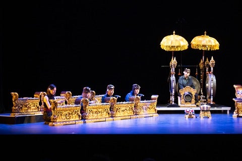 Balinese Gamelan players and instruments on stage lit in blue light